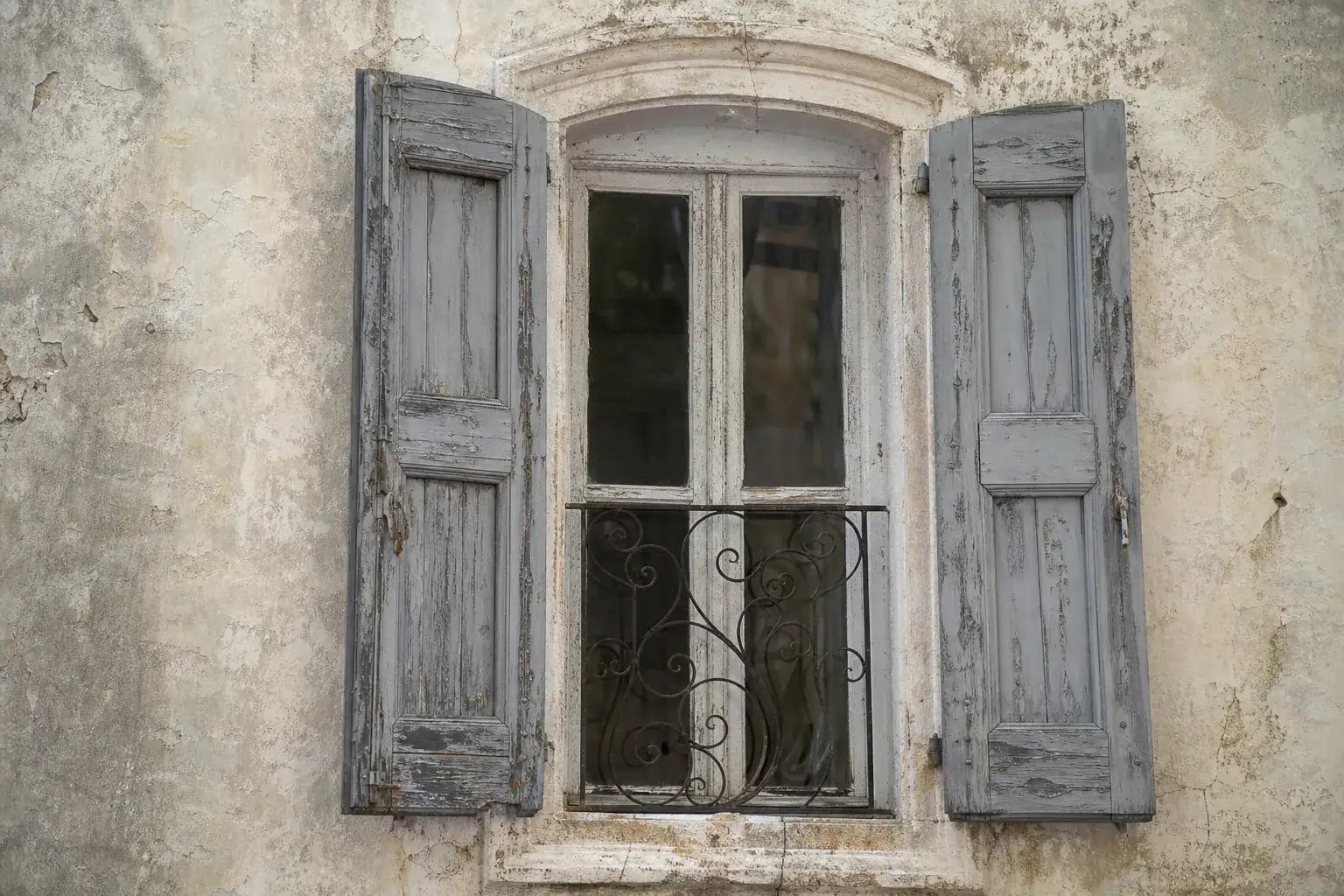 Fenêtre équipée de volets battants bois anciens et usés, peinture écaillée