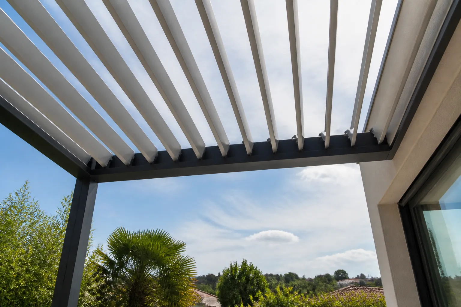 Détail d’une pergola bioclimatique aluminium aux lames orientées à mi-ouverture, vue en contre-plongée