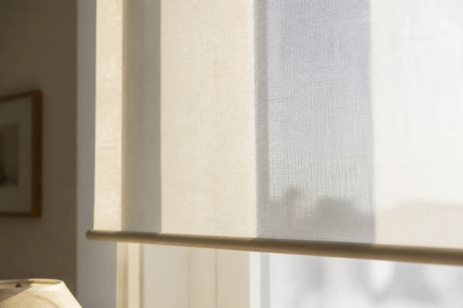 Détail d’un store enrouleur en tissu naturel filtrant la lumière dans une pièce à vivre